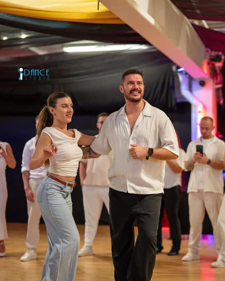 A couple dancing at El Grande White Party, with more dancers behind them.